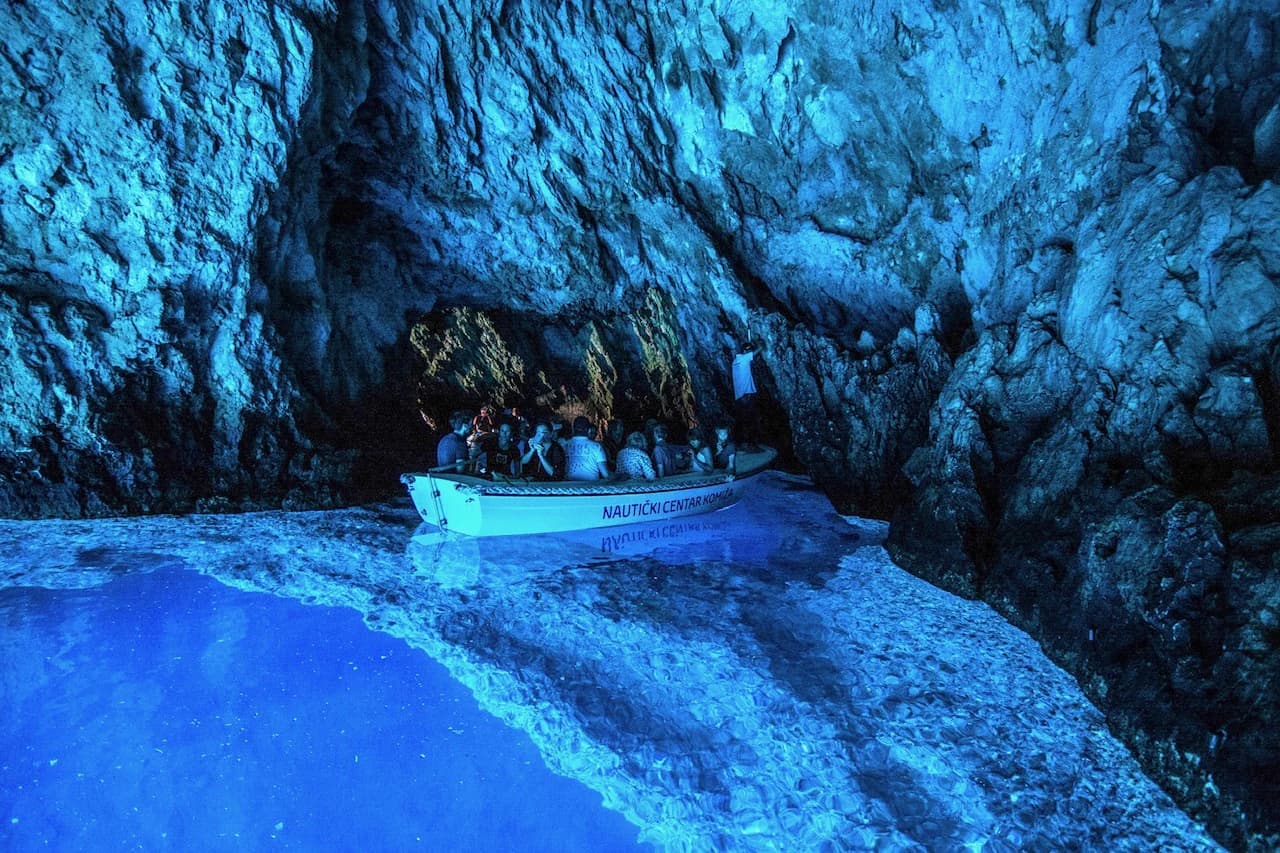 A boat of visitors inside the Blue Cave on Biševo, the water below it glowing blue. Blue Cave & 5 Island Tour