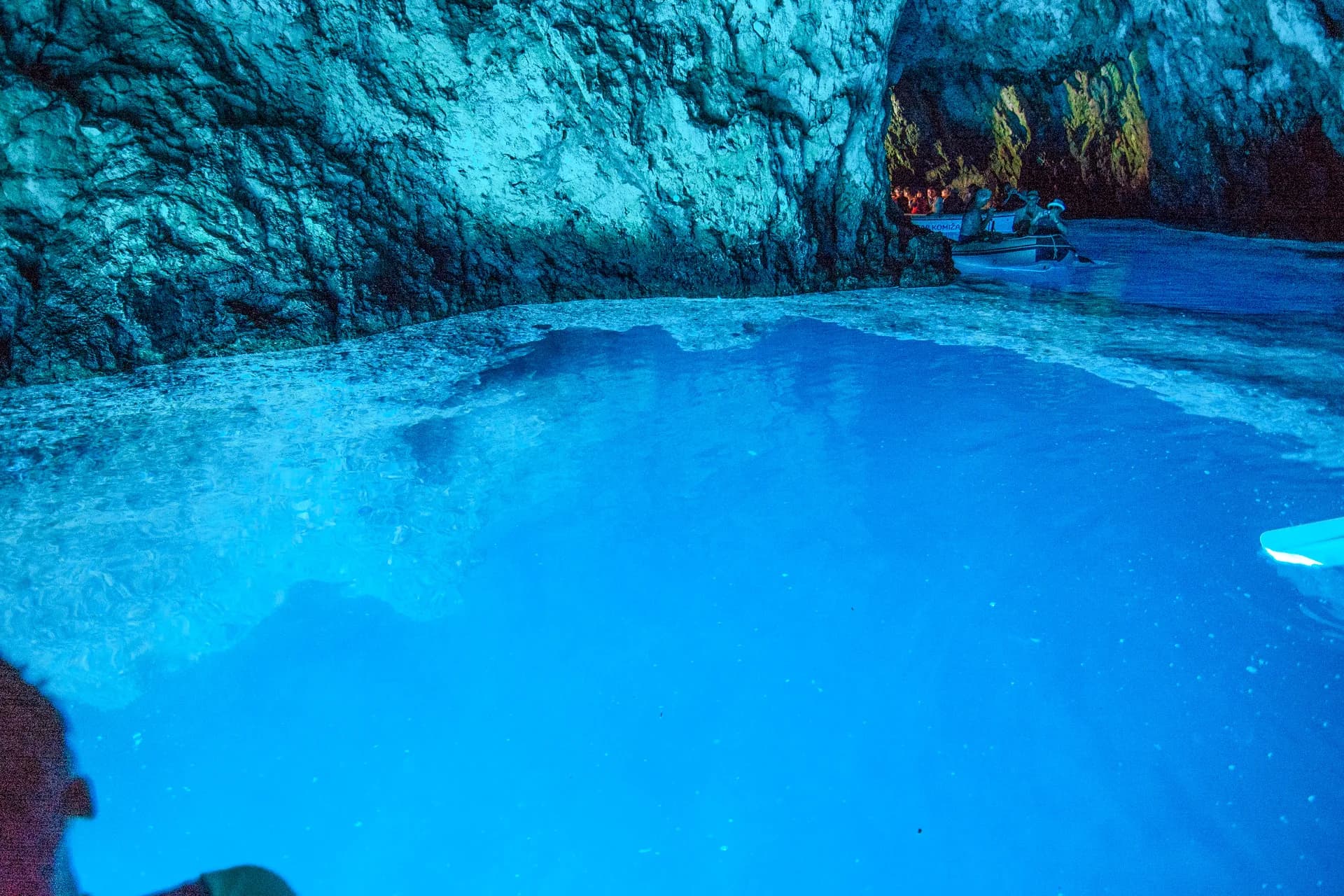 The Blue Cave pool at its brightest, electric blue against the dark limestone. Blue Cave & 5 Island Tour