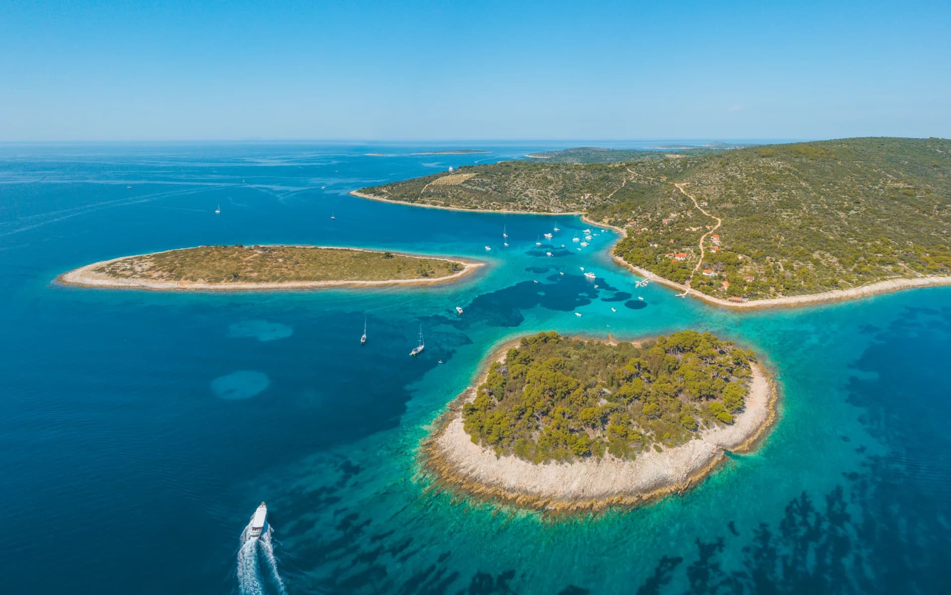 The Blue Lagoon at Drvenik from the air, the wooded islets and the turquoise shallows between them, with the open blue Adriatic beyond. Blue Lagoon, Trogir, Šolta & Brač Island