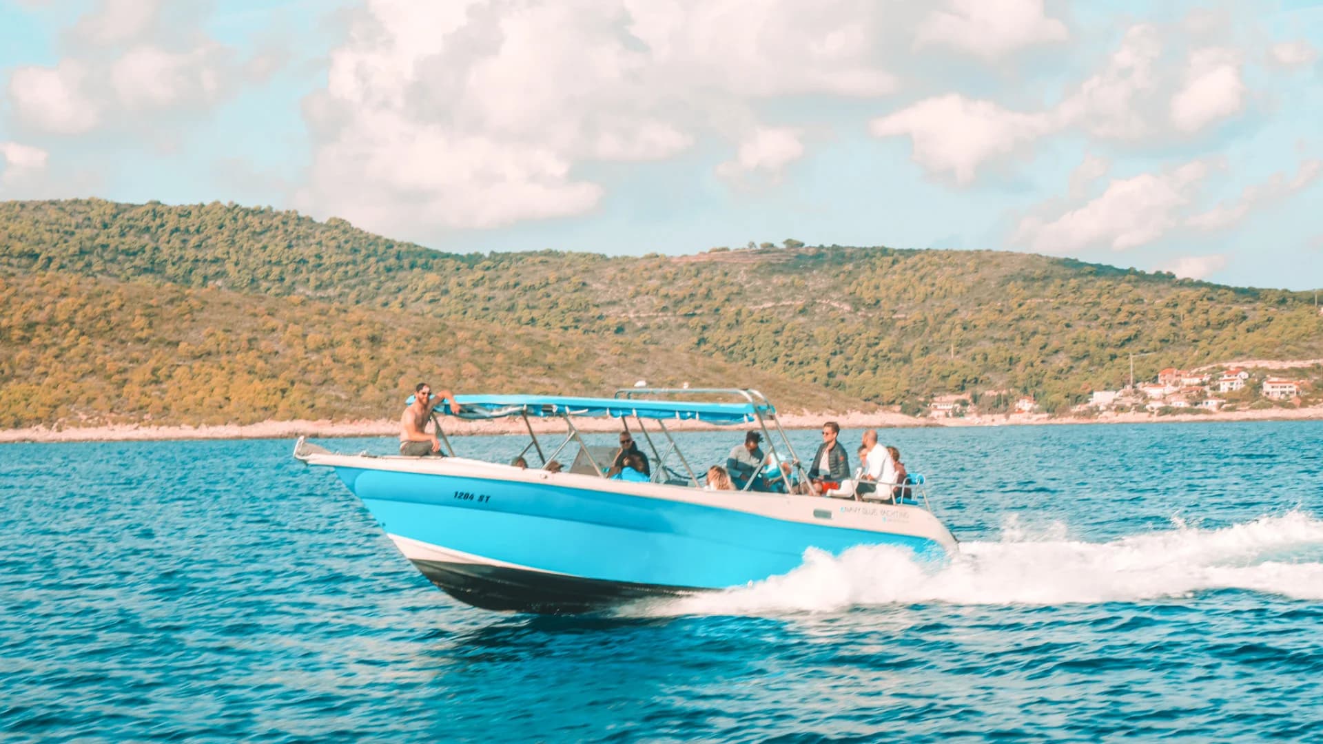 Speedboat 1204-ST passing a wooded island shore with guests aboard — Golden Cape, Hvar & Pakleni Islands