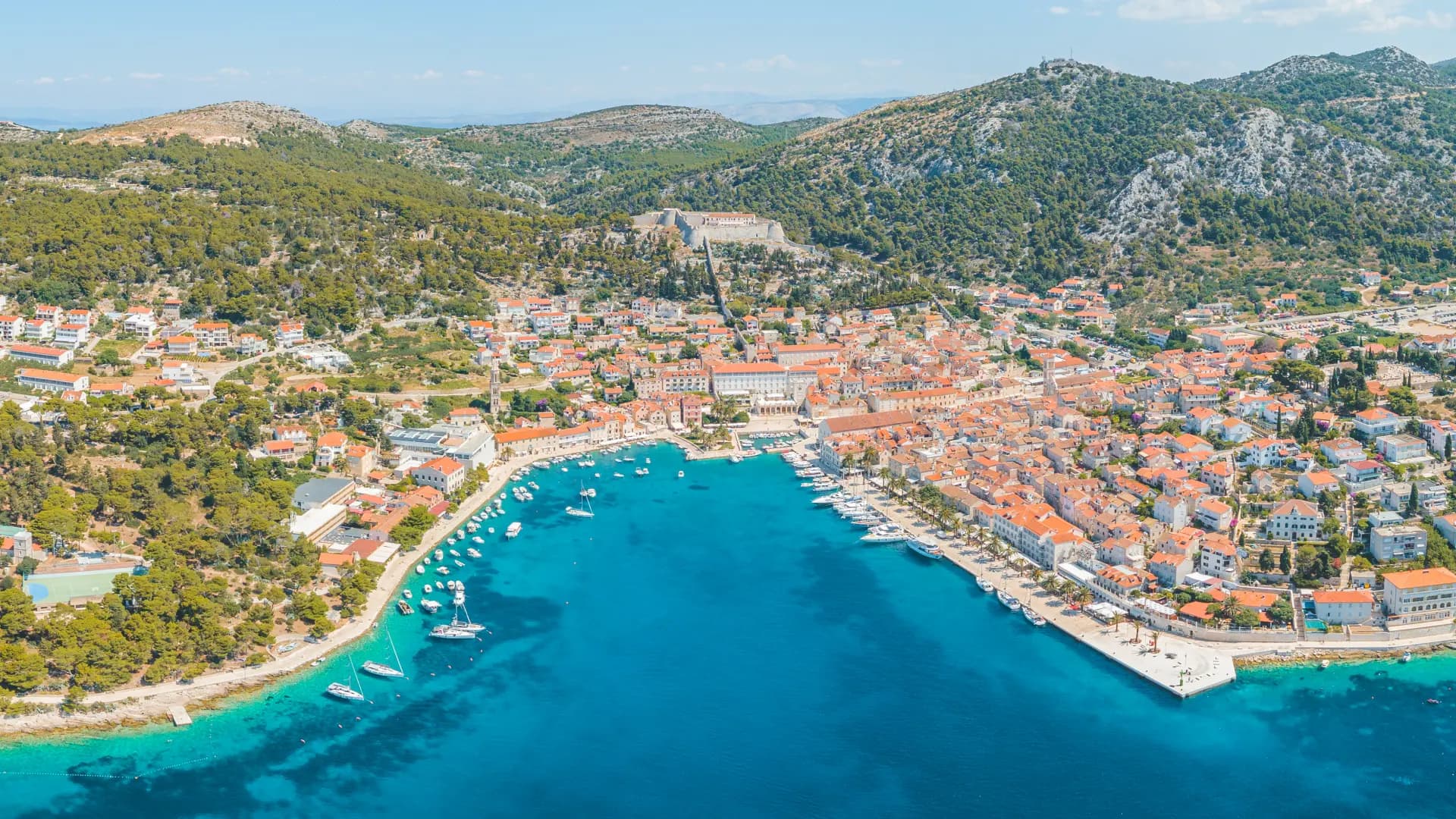 Hvar town from the air, the whole harbour full of boats below and the Fortica fortress on the hill above the red roofs. Hvar, Pakleni, Brač & Šolta Private Tour